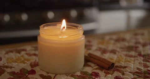 White candle lit in kitchen with cinnamon sticks dim closeup Stock Footage 249288006