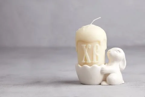 A white candle shaped like an Easter cake sits in a bunny-shaped candlestic.. Photos