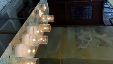 White candles flicker in a dark interior of the church, vertical format Stock Footage 302218218