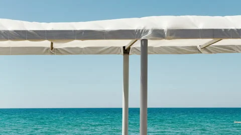 White Canopy Frames a Minimalist View of the Turquoise Ocean Horizon Stock Footage 335113015