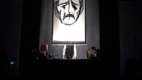 A white canvas with a drawing of an old sad face rises up. Behind the canvas is Stock Footage 242449721