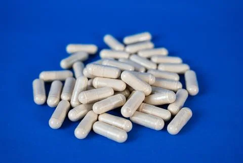 White capsules arranged on blue background Stock Photos