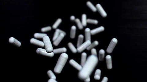 White capsules fly up and hover in the air on a black background Stock Footage 141184610