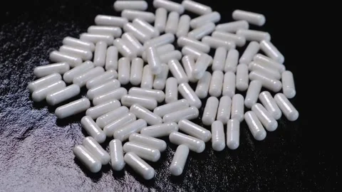 White capsules or tablets rotating on a black background Stock Footage 198026377