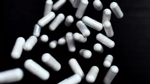 White capsules of vitamins fly up and hover in the air in slow motion Stock Footage 141184590