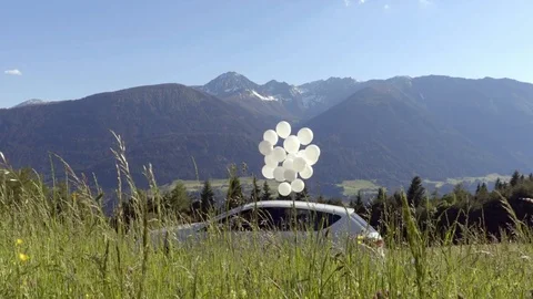 White car with balloons with the mountains on the background Stock Footage 76875971