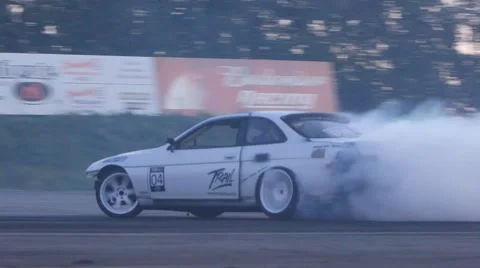 White car burns rubber leaving behind smoke trail on race track. Stock Footage 59762347