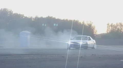 White car drifts around corner in slow motion on race track at dusk. Stock Footage 59762102