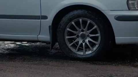 The white car drives through a large puddle on the road. Splashes fly Stock Footage 242600291