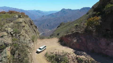 White car driving down steep dirt road in mountains, backwards aerial Stock Footage 197471246