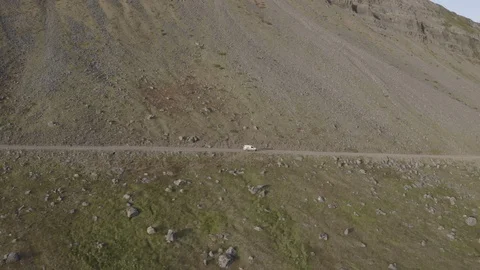 White car driving from left to right by the sea on a dusty road Stock Footage 124876406
