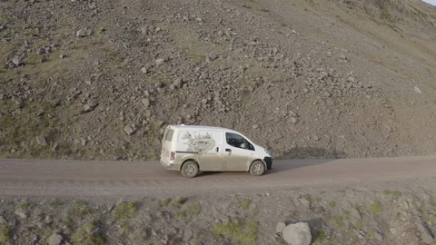 White car driving from left to right by the sea on a dusty road Stock Footage 124877078