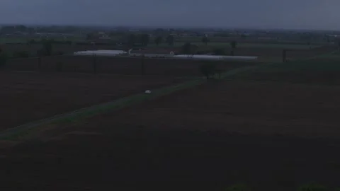 White car driving through Po Valley farmland during blue hour in northern Italy Stock Footage 336257924