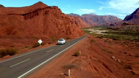 White Car Driving Through Red Rock Canyon in La Quebrada, Salta Argentina 動画素材 345970243