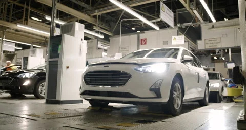 White car with lit headlights rolls through a dark industrial hall Vídeo Stock 331438826