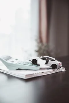 White car model with an open door rests on a calculator and notebook, repre.. Stock Photos