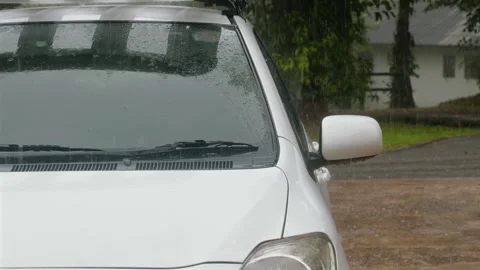 White car in rain with wet windshield and side mirror, parked outdoors Stock Footage 281274470