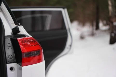 White car with red headlight and open door - winter forest Stock Photos