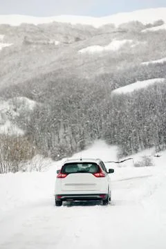 White car riding on a snow-covered road in the European Alps Stock Photos