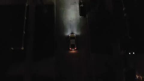 White car slowly moving down the road in a quiet neighborhood. Night Stock Footage 179932694