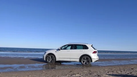 White car standing on sandy beach on background sea waves and  blue sky Stock Footage 82858129