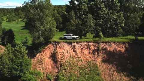 A white car stands on the edge of a cliff, the camera moves slowly, birds fly Stock Footage 277985192