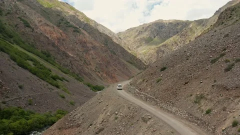 White car taking corner on a dangerous dirt road high in the mountains Stock Footage 145088889