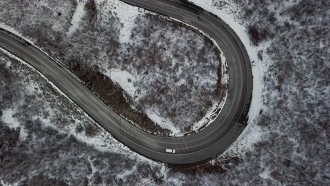 White car winds up snowy mountain road. 4k aerial footage. Stock Footage 232819004