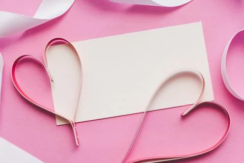 White card with copy space, two red paper hearts on a pink background Stock Photos