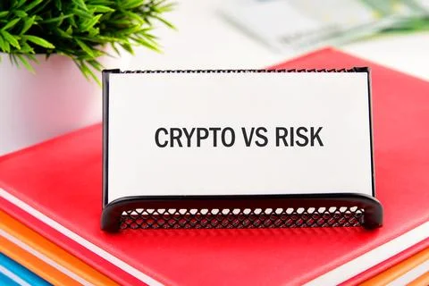 A white card with CRYPTO VS RISK rests on a stack of red, orange, and blue .. Stock Photos