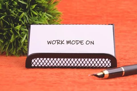 A white card reads Work Mode On, set in a black holder on an orange desk Foto stock