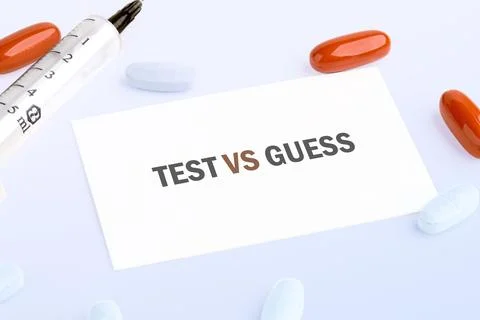 A white card with the words TEST VS GUESS is surrounded by a medical syringe  Stock Photos