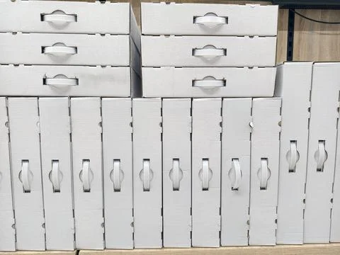 White cardboard boxes with handles placed in aligned rows on electronics st.. Stock Photos