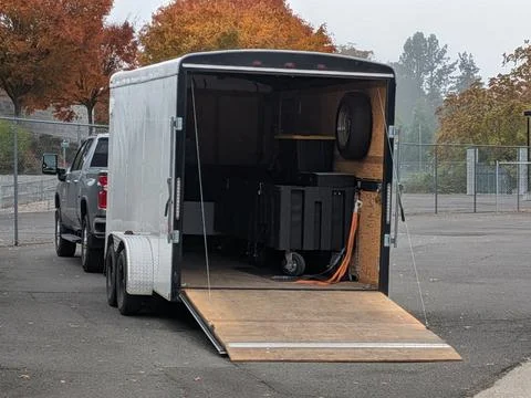 White cargo trailer pulled by a truck with its back door open Photos