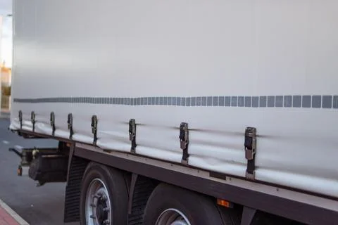 White cargo truck side view showcasing the tarpaulin cover with metal latch.. Fotos de archivo