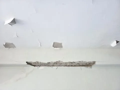 White ceiling corner with severe peeling paint and exposed concrete 库存照片