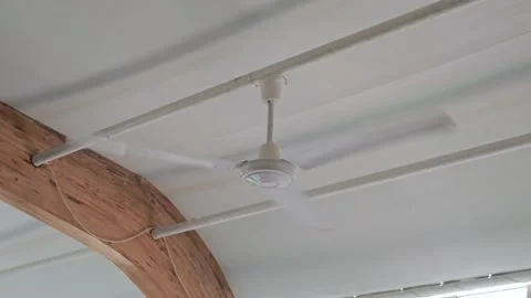 A white ceiling fan spins and cools the air by dispersing it around the room Stock Footage 202076649