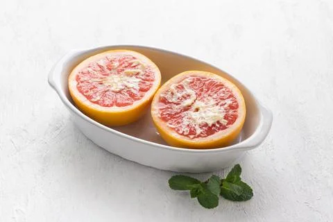 White ceramic baking dish red grapefruit halves smeared with butter on a li.. Stock Photos