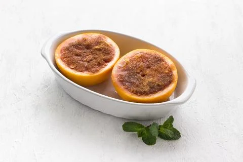 White ceramic baking dish with red grapefruit halves smeared with butter and Stock Photos