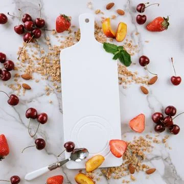 White ceramic board on a marble background, among fruits. Stock Photos