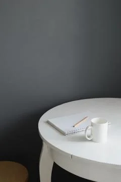 White ceramic coffee cup with notepad and pencil on white wooden table in sca Stock Photos
