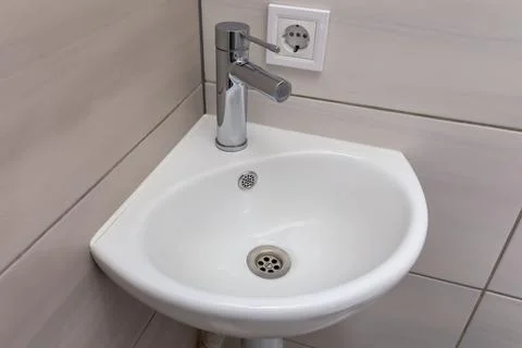 White ceramic corner washbasin with single handle mixer on tiled wall Photos