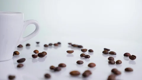 White ceramic cup with coffee beans rotating on a white background. Stock Footage 129363373