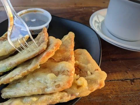 White ceramic cup of hot black coffee and fried tempeh or tempeh mendoan on.. Stock Photos