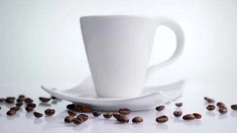 White ceramic cup with roasted coffee beans rotating on a white background. Stock Footage 129592972