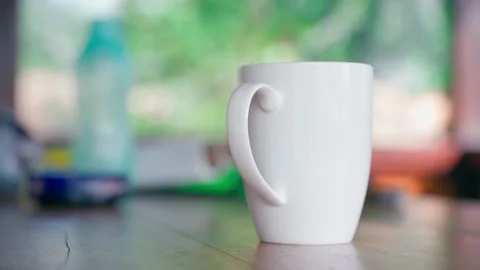 White ceramic cup on the table close-up on a blurred background, smooth parallax Stock Footage 233567169
