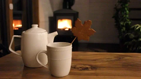 White ceramic cup, teapot stand on wooden table. Fire blaze flames in black Stock Footage 257888258