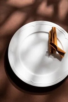 White ceramic dessert plates with cinnamon on brown background. Food concept wit Stock Photos