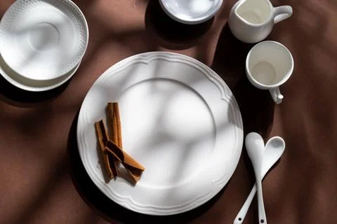 White ceramic dessert plates with cinnamon on brown background. Food concept wit Stock Photos