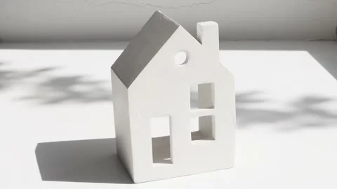 White ceramic house on a light gray background with sunlight Stock Footage 196114761